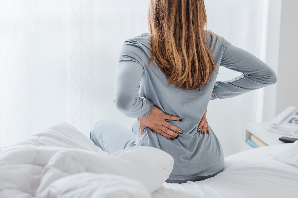 Eine Frau hat Rückenschmerzen beim Aufstehen