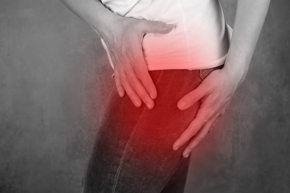 Eine Frau hält beim Gehen ihren schmerzenden Oberschenkel fest.